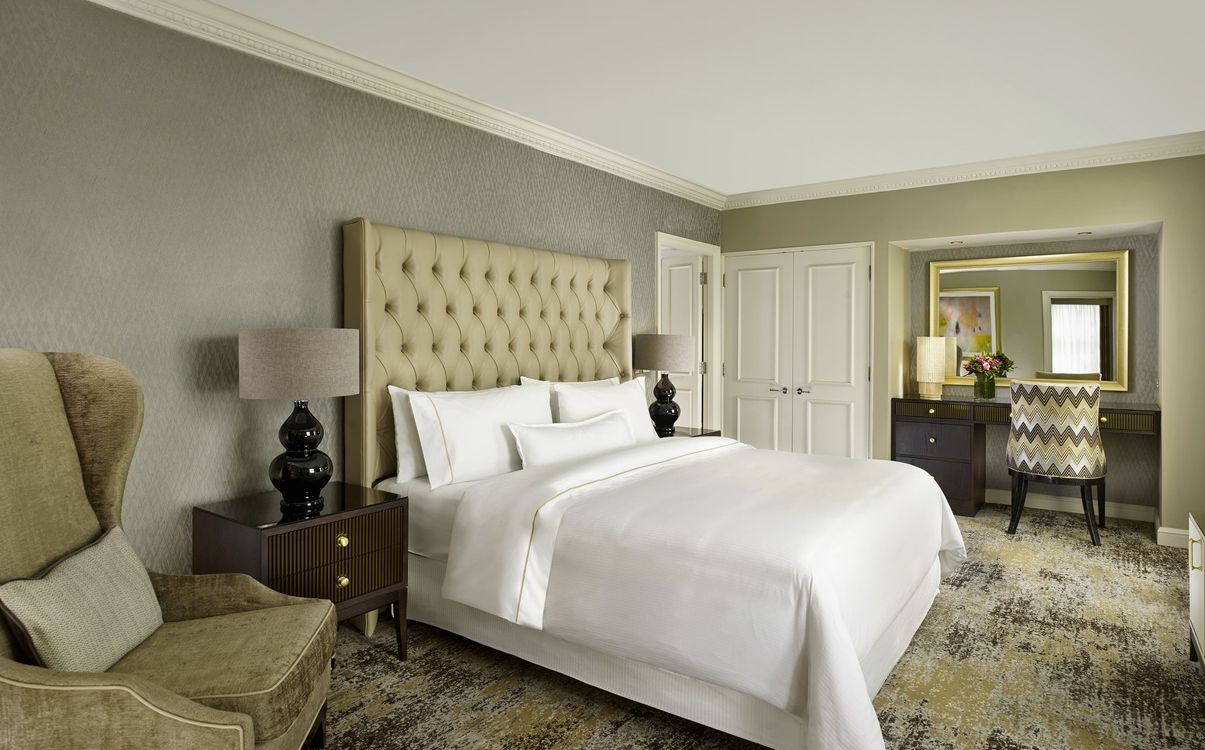 Large deluxe suite bedroom with chairs and neutral toned décor