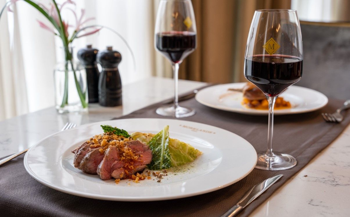 Two dinner dishes on table with red wine glasses in The College Green Hotel Dublin